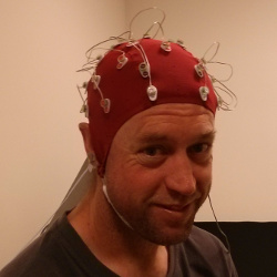 A nice picture of Ben Howell wearing a red electroencephalography cap with lots of sensors attached